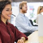 Call center agents using an intelligent dialer dashboard on their computers, showing active calls, call stats, and predictive dialing in action.