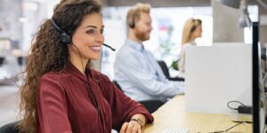 Call center agents using an intelligent dialer dashboard on their computers, showing active calls, call stats, and predictive dialing in action.