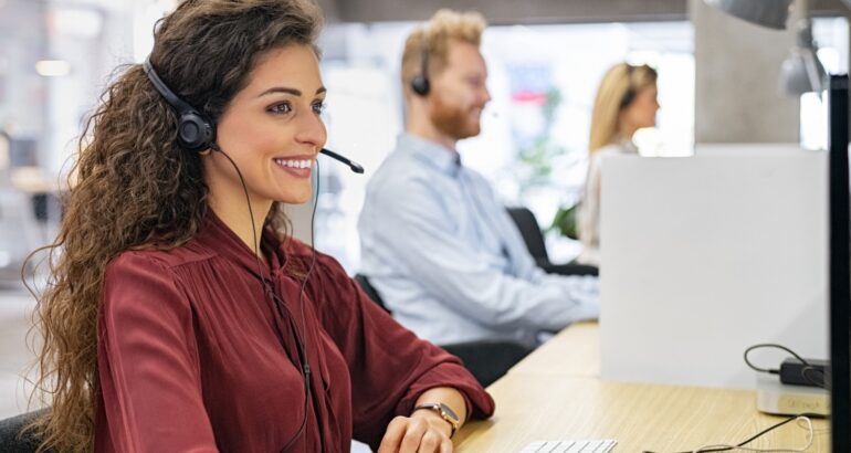 Call center agents using an intelligent dialer dashboard on their computers, showing active calls, call stats, and predictive dialing in action.